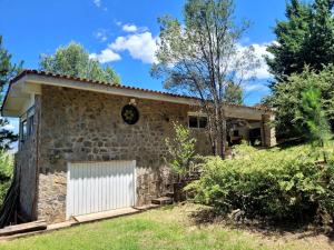 a stone house with a white garage at Loft on Los Reartes River, Intiyaco in Villa Berna