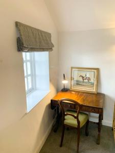 a wooden desk with a chair next to a window at 2 Stable Cottage, Llanbethery in Llancarfan