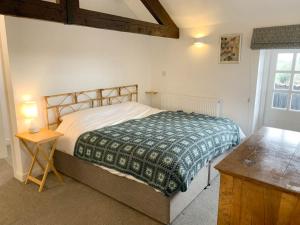 a bedroom with a bed and a table and a window at 2 Stable Cottage, Llanbethery in Llancarfan
