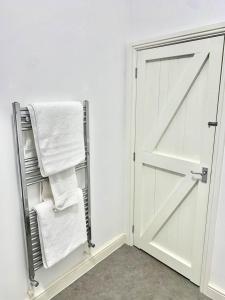 a bathroom with a white door and towels at 2 Stable Cottage, Llanbethery in Llancarvan
