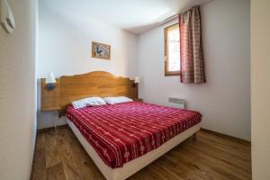a bedroom with a bed with a red comforter and a window at Appartement à la Montagne The view in Albiez-Montrond