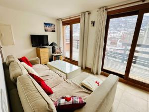 a living room with a couch and a large window at Le Coucou - Grand chalet - Parking - WIFI - ALLOS - 10adul+2enf in Allos