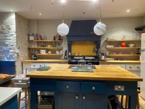 uma cozinha com uma ilha azul com bancada de madeira em Kennet House em Ludlow