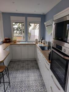 cocina con armarios blancos, fregadero y microondas en Maison familiale centre ville avec Parking, en Le Mans