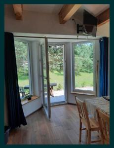 een kamer met glazen schuifdeuren en een tafel en stoelen bij Uroczy domek na Mazurach, Pilec 59 in Pilec