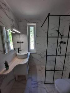 a white bathroom with a sink and a mirror at Uroczy domek na Mazurach, Pilec 59 in Pilec