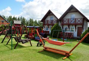 a yard with a playground with swings and a house at Domki wczasowe u Ewy in Chłopy