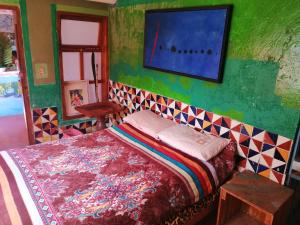 1 dormitorio con 1 cama y TV en la pared en Casa Kasa Hostel, en San Cristóbal de Las Casas