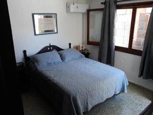 Suíte في بونتا دل إستي: غرفة نوم بسرير لحاف ازرق ونافذة