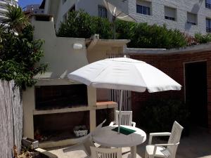 Suíte في بونتا دل إستي: طاولة بيضاء وكراسي مع مظلة