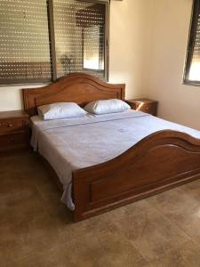 a bedroom with a large wooden bed with two pillows at Rosa Farm, Jerash Most Beautiful Villa in Jerash