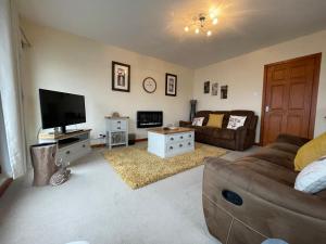 een woonkamer met een bank en een flatscreen-tv bij Hector's Bothy flat in Kyle of Lochalsh