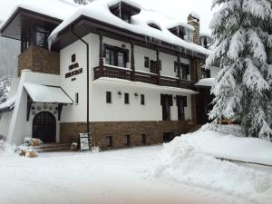 a building covered in snow with a pile of snow at Hanul Haiducilor in Obarsia-Lotrului