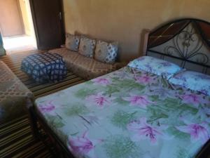 a bedroom with a bed with a floral bedspread at Gite Amoudou in Ouarzazate