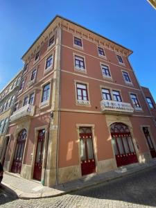 een groot bakstenen gebouw met rode deuren op een straat bij Porto.Leça - Studios and Apts (Apt H) in Leça da Palmeira
