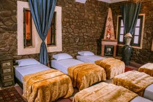 Pokój z 4 łóżkami i kamienną ścianą w obiekcie Riad Kasbah Omar w mieście Ourika