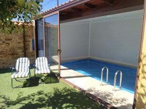 Un patio con dos sillas y una piscina. en Astorga. León. Piscina. Casa Val de San Lorenzo., en Val de San Lorenzo