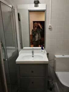 una donna che scatta una foto in uno specchio del bagno di Vovo House a Lisbona