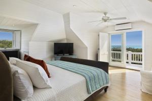 a white bedroom with a bed and a television at Miranda House home in Governorʼs Harbour