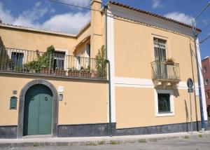 a yellow building with a blue door and a balcony at B&B VELARDI in Viagrande