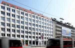 un gran edificio blanco con un autobús delante en Hotel Attaché contactless en Viena
