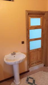 baño con lavabo blanco y puerta en Chez L'habitant Brahim kanih 