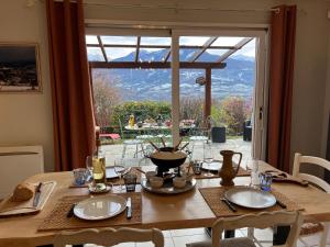 a dining room table with a view of a patio at MAISON DES VIGNES in Embrun