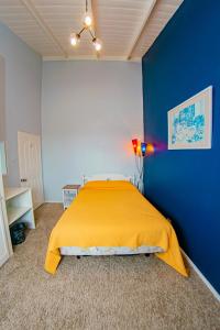 1 dormitorio con cama amarilla y pared azul en JR Apartments, en Georgetown