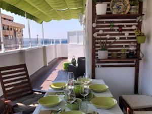 una mesa con platos y copas de vino en el balcón en ÁTICO VICTORIA BEACH, en Cádiz