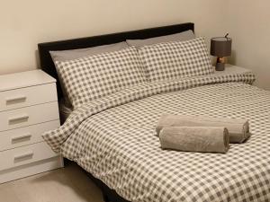 a bed with a black and white checked comforter and a night stand at Heronsgate GH009 in Abbey Wood