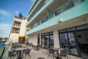 a patio with tables and chairs on a building at Hotel Ana Eforie in Eforie Nord