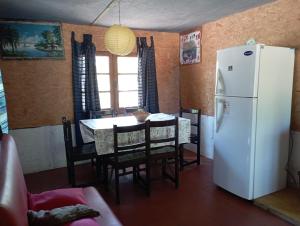 cocina con mesa y nevera blanca en Natural Mistic, en Punta del Diablo