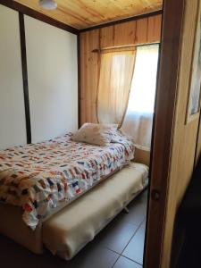 Cama pequeña en habitación con ventana en RdA Cabaña en Pichilemu