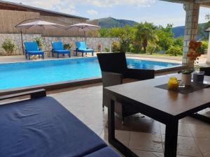 stół i krzesła przy basenie w obiekcie Apartment Oaza w mieście Mostar