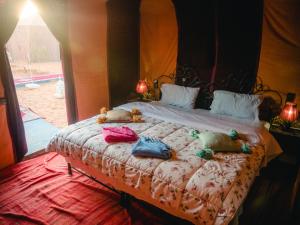 a bedroom with a bed with stuffed animals on it at Desert Camp Erg Chebbi in Merzouga +36 photos