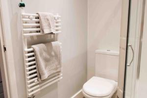 a bathroom with a toilet and towels on a rack at Clee Ness - 1 bed maisonette, on the seafront in Cleethorpes