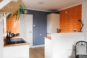 a kitchen with a sink and an orange tile wall at Clee Ness - 1 bed maisonette, on the seafront in Cleethorpes
