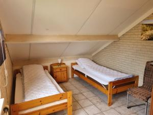 two beds in a room with a chair at Vakantiehuis Ome Wim op 't Hoogelandt in De Koog
