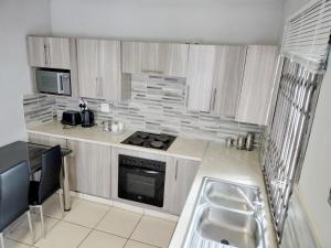 een kleine keuken met een fornuis en een wastafel bij Sunrise Guesthouse in Pretoria