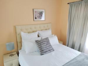 een slaapkamer met een wit bed met witte kussens bij Sunrise Guesthouse in Pretoria