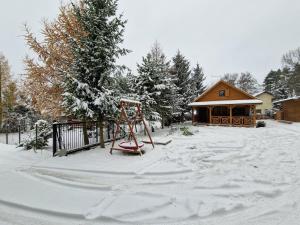 un parque infantil en un patio cubierto de nieve en Woda i Las en Jeżewo