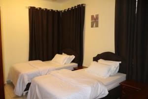 two beds in a room with black curtains at Al-Mwadda Hotel in Seeb