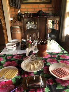 einen Tisch mit Tellern und Geschirr auf einem floralen Tischtuch in der Unterkunft Chalés Vida Verde in Bom Jardim de Minas