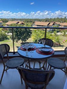 stół z kieliszkami do wina i krzesłami na balkonie w obiekcie Flat novo no Eco Resort w mieście Tamandaré