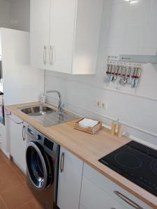 een keuken met een wastafel en een wasmachine bij Albatros Golf Costa Esuri Ayamonte Huelva in Huelva