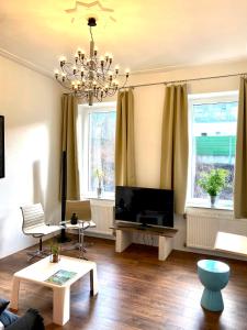a living room with a television and a chandelier at Chez Coco Apartment 2 Aachen in Aachen