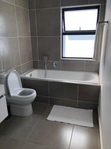 a bathroom with a tub and a toilet and a window at Ballito 134 in Ballito