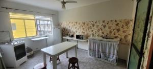a small kitchen with a table and a window at Suítes Suarão in Itanhaém