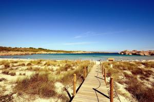 a wooden path to a beach with people in the water at Apartamento Albatros-Son Parc Menorca in Son Parc
