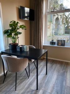 Bed and Breakfast Stinzenflora في Cornjum: طاولة سوداء وكرسي في غرفة مع نافذة